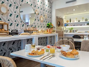 A breakfast buffet with various food items and beverages, a mirror, and decorative wall patterns.