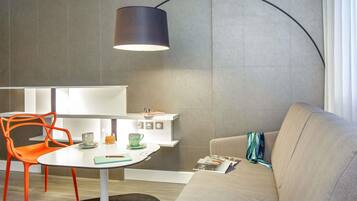A modern living room with a round table, orange chairs, a sofa, and a floor lamp.