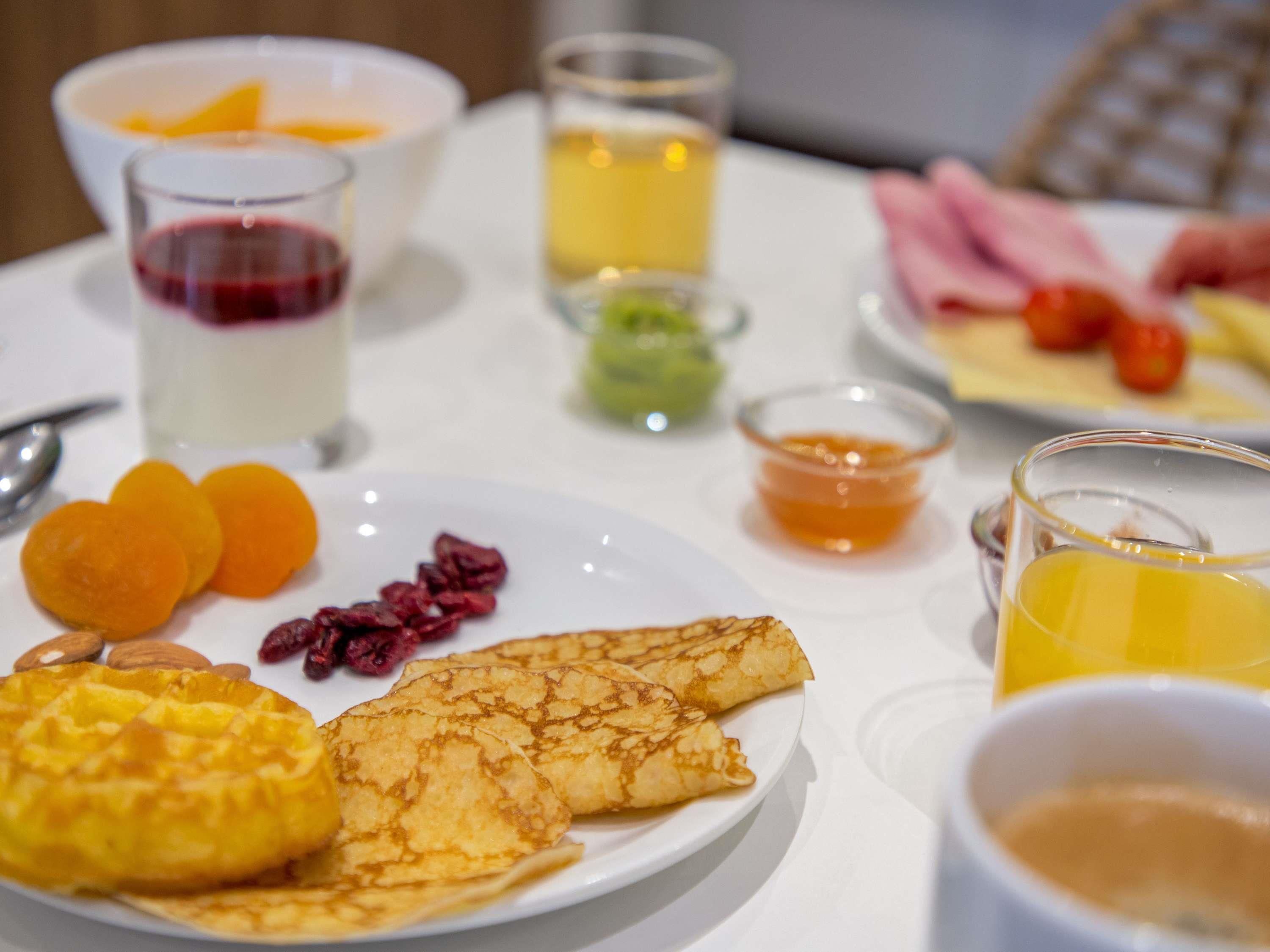 A breakfast table with various food items and drinks.