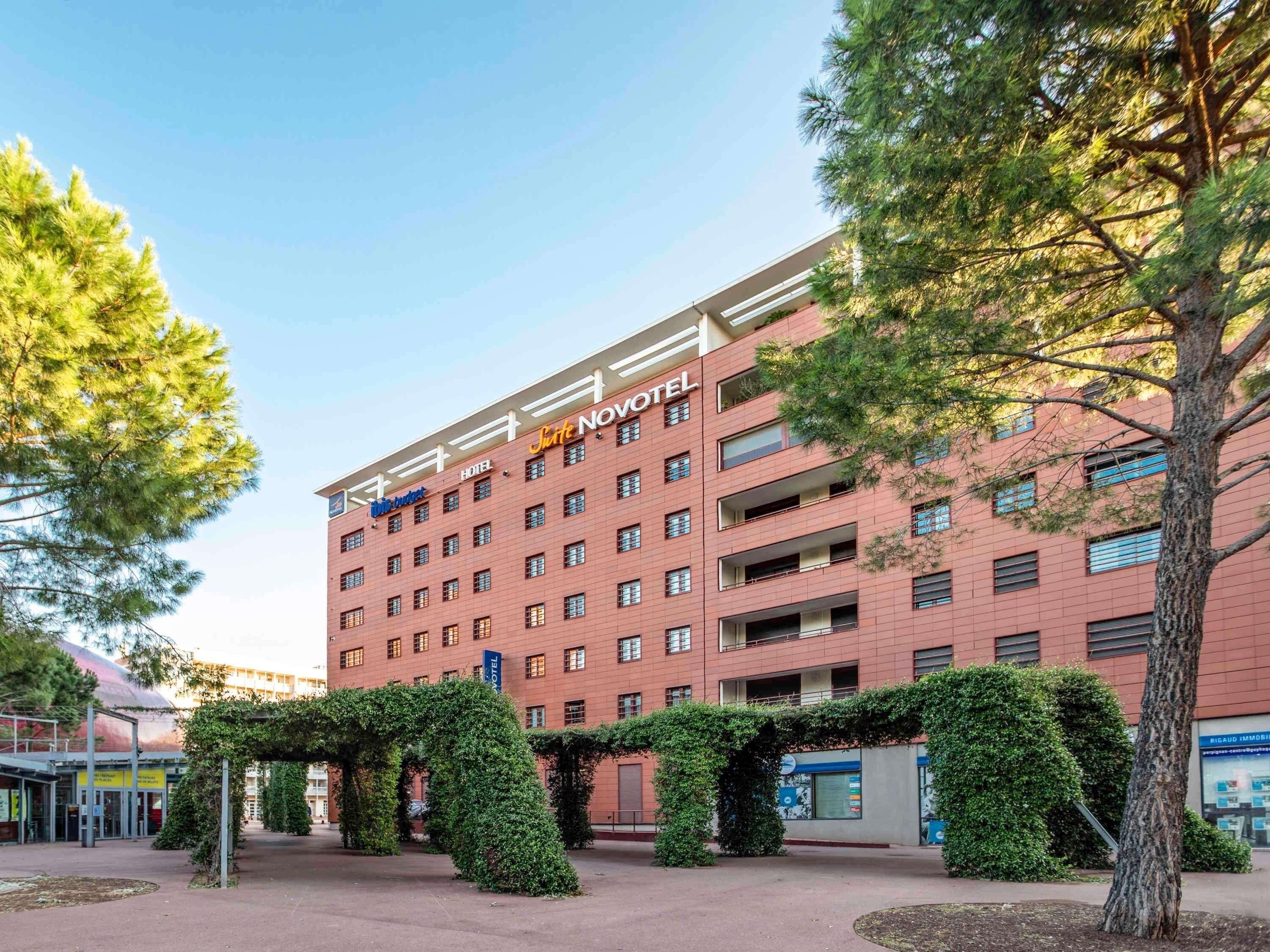 Un edificio de hotel con varios pisos, cielo despejado y vegetación circundante.