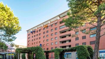 Un edificio de hotel con varios pisos, cielo despejado y vegetación circundante.