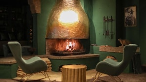 Een gezellige kamer met een grote, ronde houtkachel, twee schommelstoelen en een kleine tafel.
