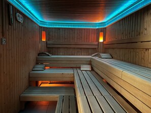 A sauna with wooden benches and benches, a ceiling with blue lighting, and wall-mounted heaters. - Hit the Sky (Sankt Anton am Arlberg)