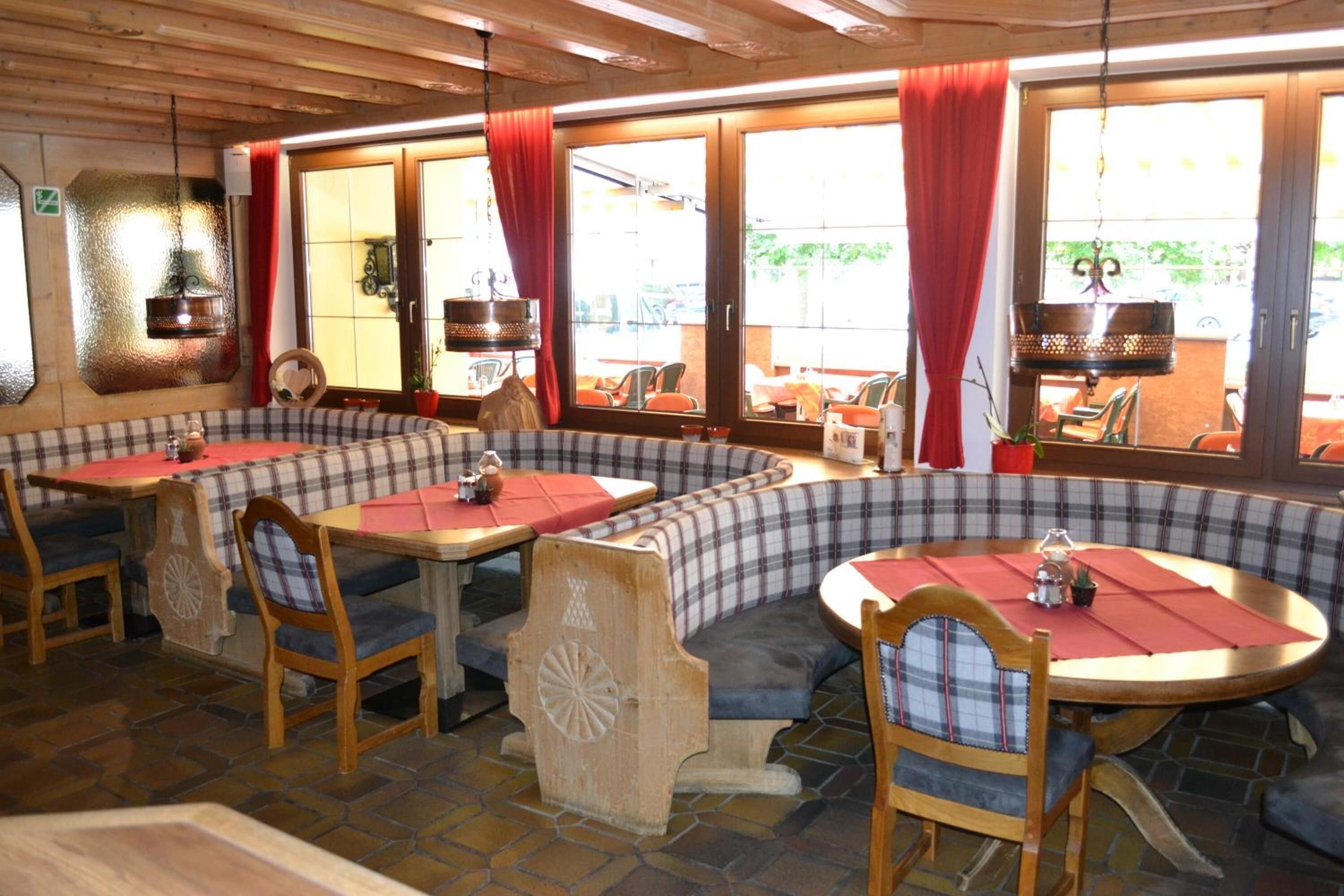 A restaurant with round tables and booths, featuring plaid upholstery and wooden accents.