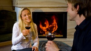 Una persona sosteniendo una copa de vino frente a una chimenea.