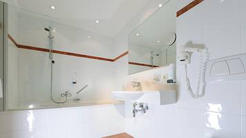 A modern bathroom with a glass shower enclosure, a white sink, and a mirror.