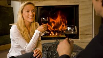 A person holding a wine glass in front of a fireplace.