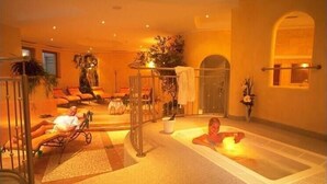 Un espacio de spa con un jacuzzi, sillones de descanso y una zona de estar con una planta.