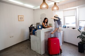 A reception desk with a computer, a blue folder, and a red suitcase.