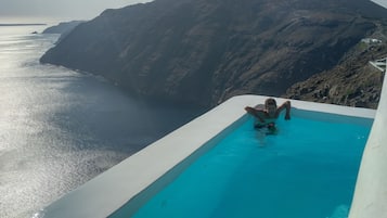Relax by the serene infinity pool overlooking the ocean and distant mountains.