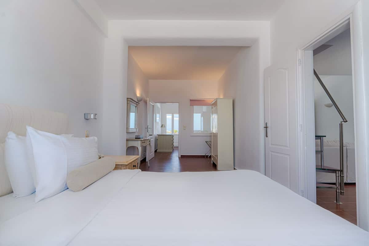 A bedroom with a large bed, bedside tables, a desk, and a wardrobe.