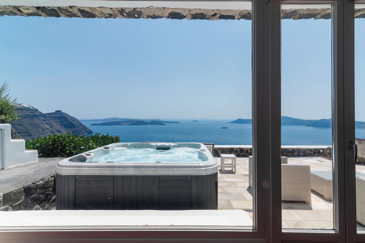 A hot tub on a patio with a view of the sea and mountains.