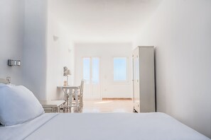 A minimalist bedroom with a bed, a desk, and a wardrobe.