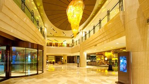 A spacious lobby with a high ceiling, a large chandelier, and a digital information kiosk.