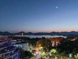 Ein beleuchtetes Stadtbild bei Nacht mit einem Fluss, Bergen im Hintergrund und einem Gebäude mit leuchtenden Schildern.