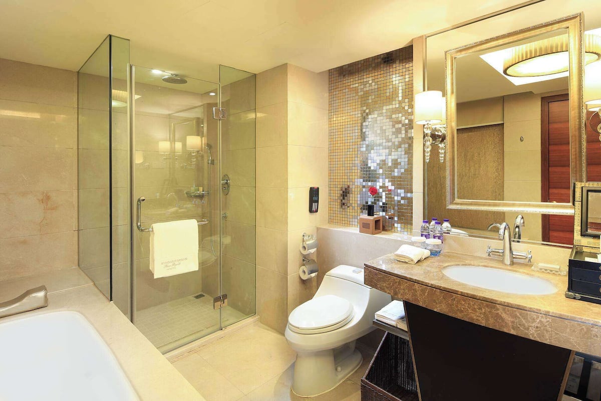 A modern bathroom with a glass shower enclosure, a toilet, a sink with a vanity, and a large mirror.