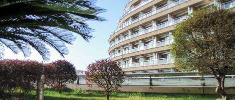 A modern building with multiple balconies and a well-maintained garden area with trees and a wooden pathway.