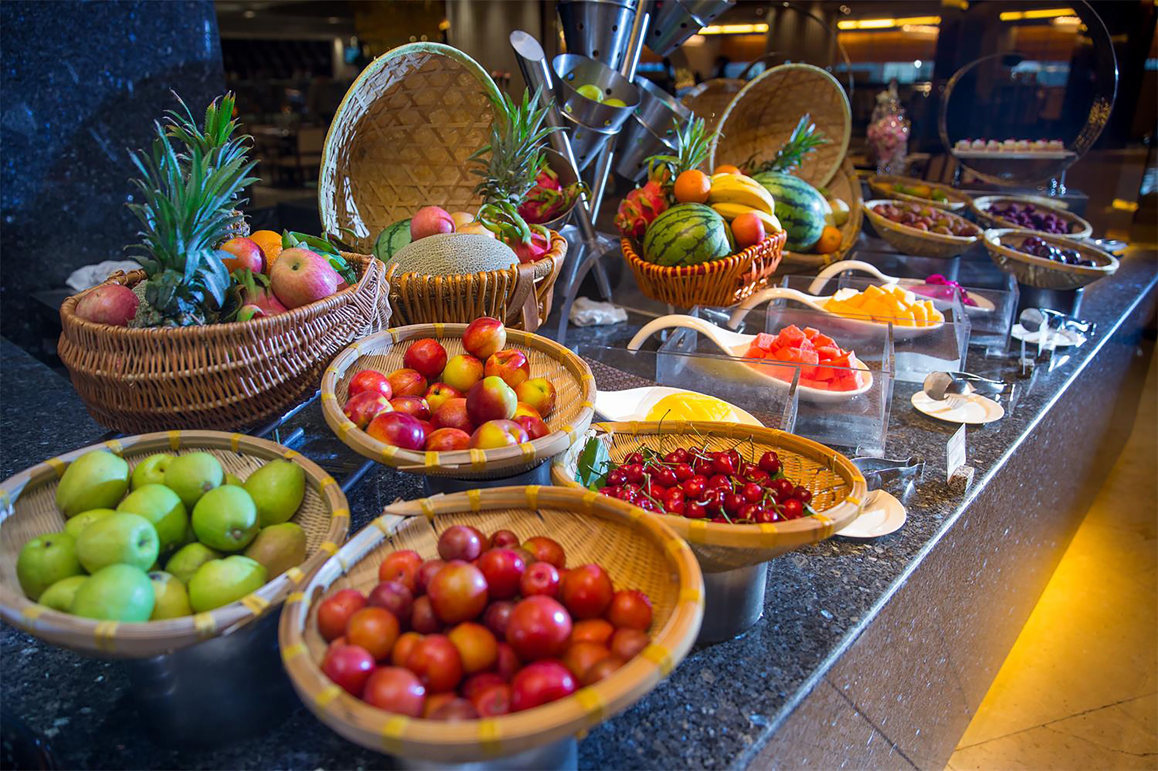 Un bufé con diversas frutas y verduras expuestas en cestas y tazones.
