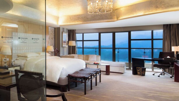 A hotel room with a large bed, a sofa, a desk, and a view of the ocean.