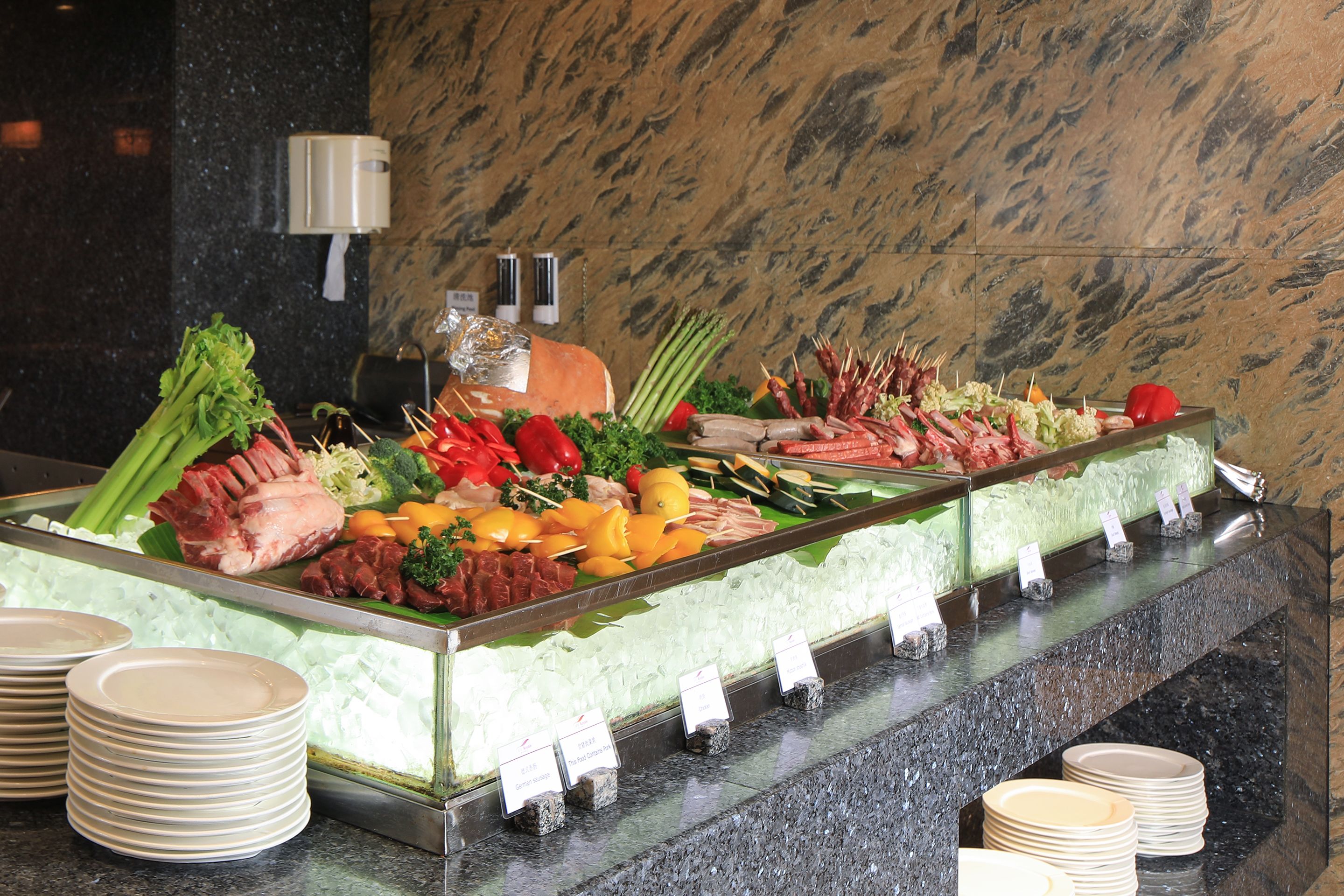 Un bufé con diversas carnes, verduras y frutas.