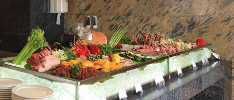 Un bufé con diversas carnes, verduras y frutas.