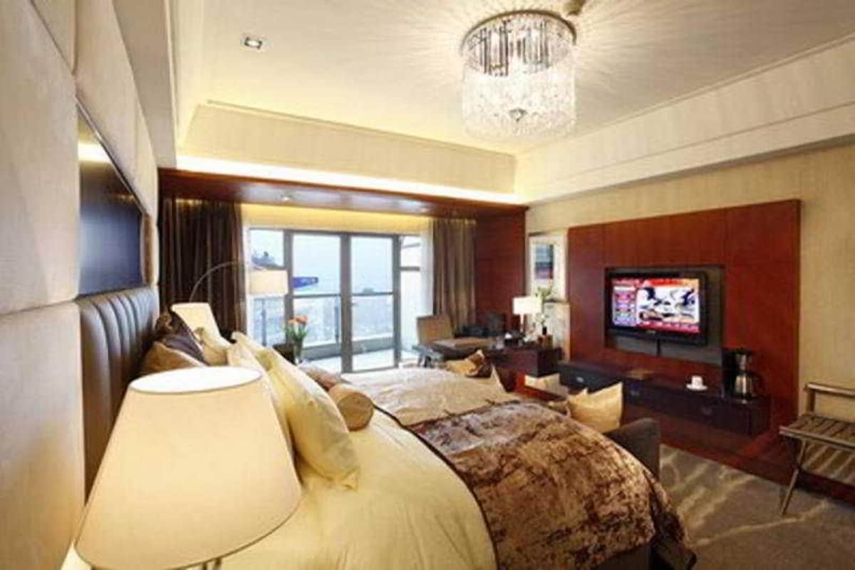 Habitación de hotel con una cama grande, televisión, escritorio y vistas al exterior.