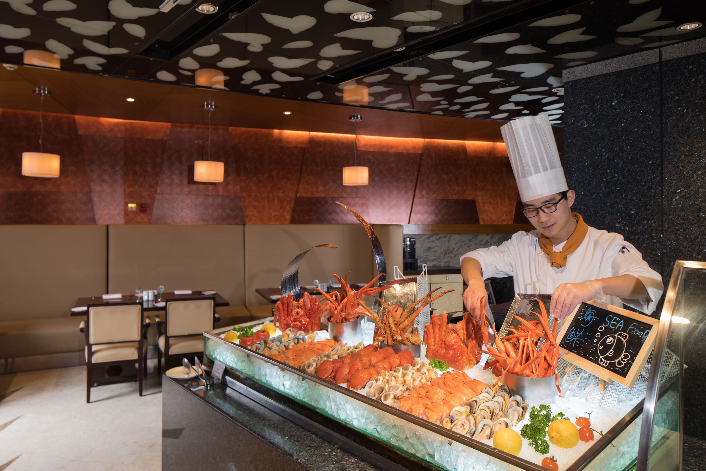 A seafood display with various types of seafood, a chef in uniform, and a chalkboard sign.