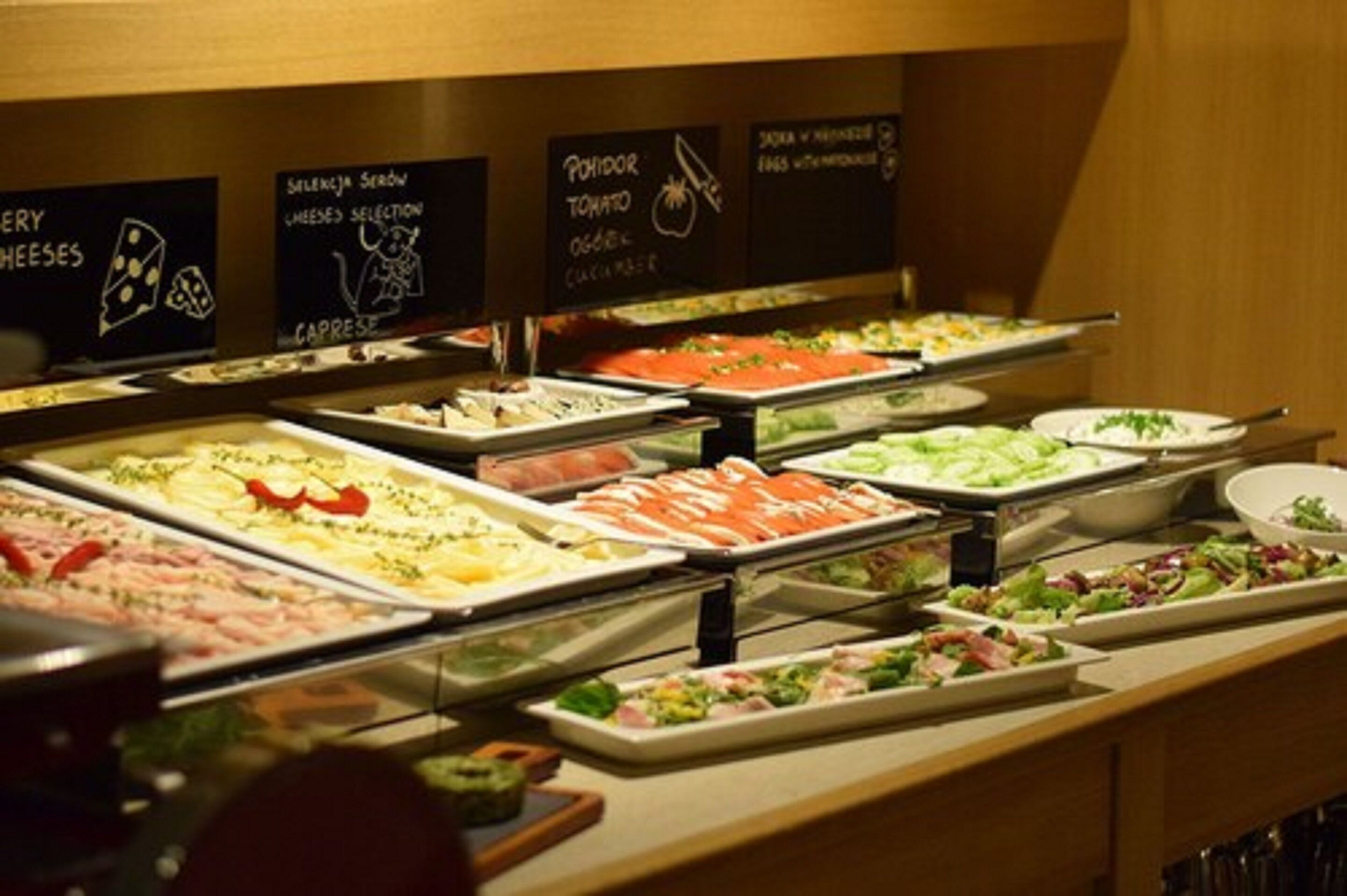 Un bufé con diversas opciones de comida, incluyendo quesos, ensalada caprese y salmón ahumado.