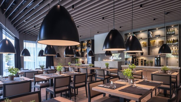 A modern restaurant with high ceilings, pendant lighting, and a bar area with wine bottles. - Hotel Ilonn (Poznan)