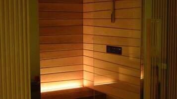 Un sauna avec des parois en lattes de bois, un panneau de commande et une porte en verre.