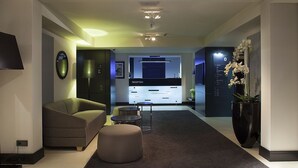 A modern hotel lobby with a reception desk, seating area, and a large potted plant. - Hotel Ilonn (Poznan)