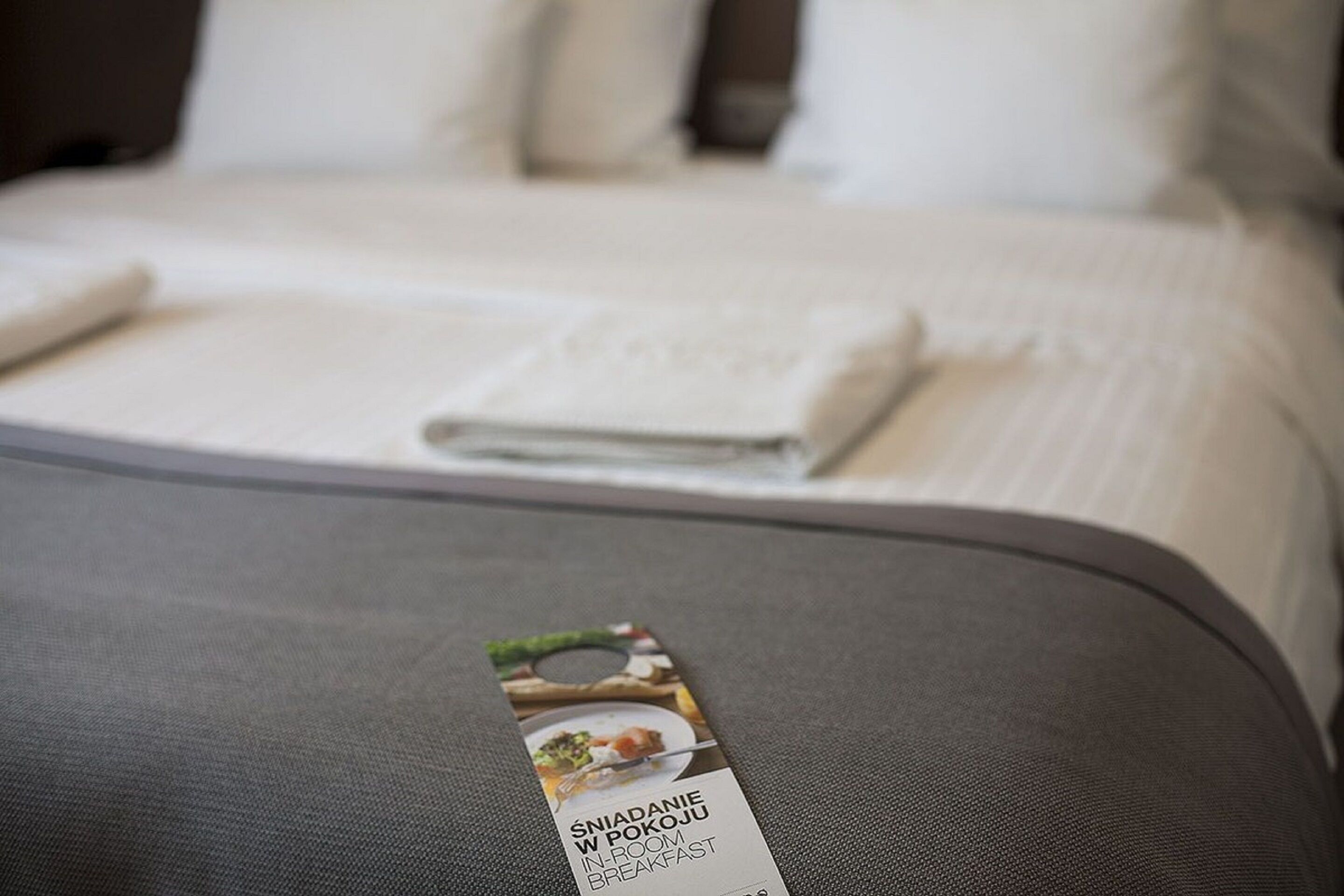 A neatly made bed with a folded white blanket and a brochure on the bed.