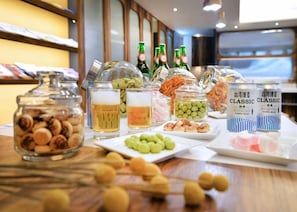 A buffet table with various food items and drinks, including jars of pickles, green grapes, and packaged snacks. - Just Sleep Taipei Linsen (Taipei)