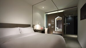 A hotel room with a large bed, a desk with a lamp, a chair, and a mirror. - Just Sleep Taipei Linsen (Taipei)