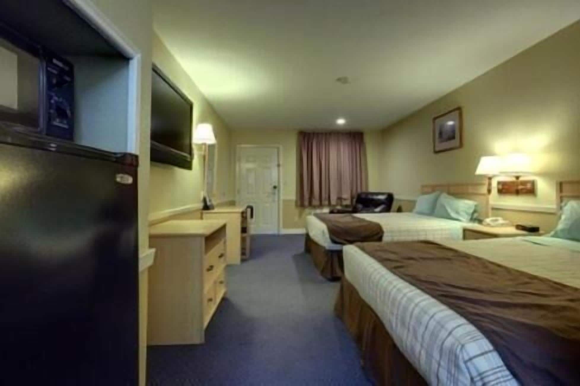 Een hotelkamer met twee bedden, een bureau, een televisie en een badkamer.