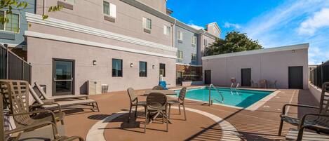 A pool area with lounge chairs and a pool.