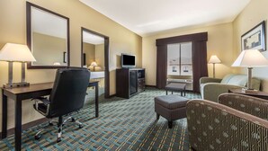 A hotel room with a desk, chair, television, and two armchairs. - Days Inn & Suites by Wyndham Mineral Wells (Mineral Wells)