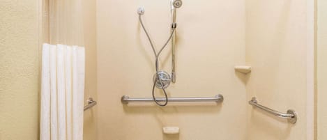 A bathroom with a shower, grab bars, a towel rack, and a soap dish.