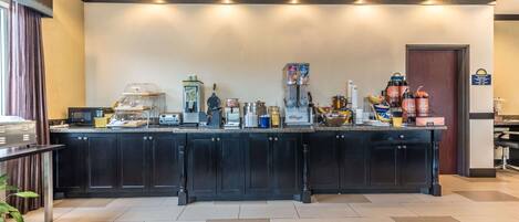 A hotel reception area with a counter, various appliances, and a sign indicating amenities.