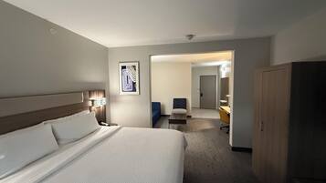 Quarto de hotel com uma cama grande, uma escrivaninha, uma cadeira e um guarda-roupa.