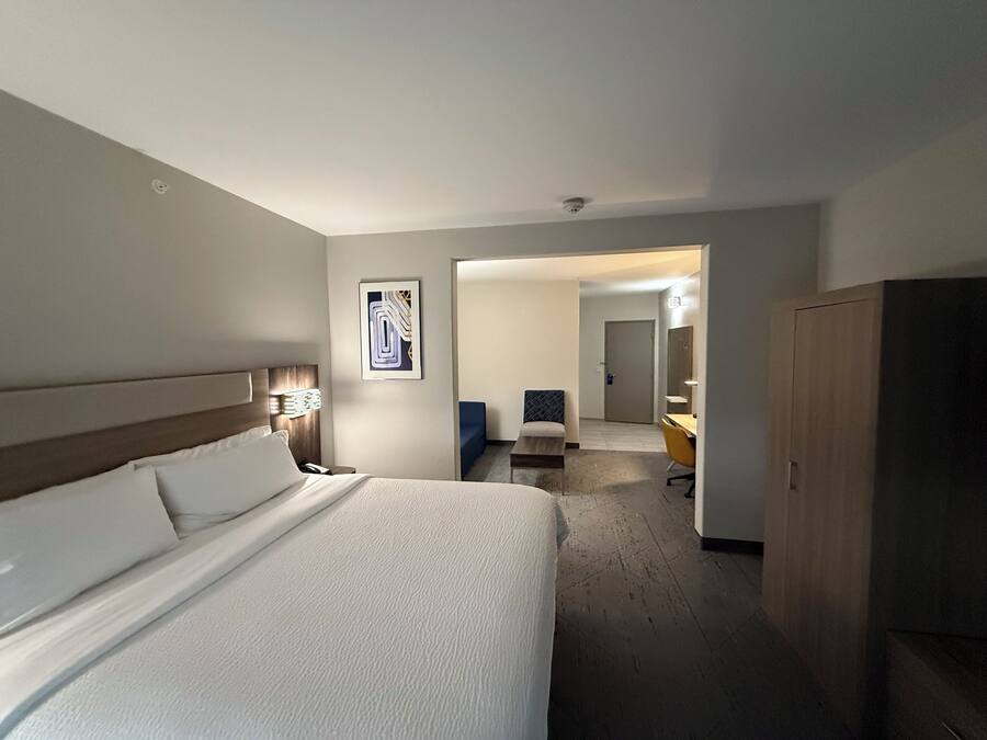 Quarto de hotel com uma cama grande, uma escrivaninha, uma cadeira e um guarda-roupa.