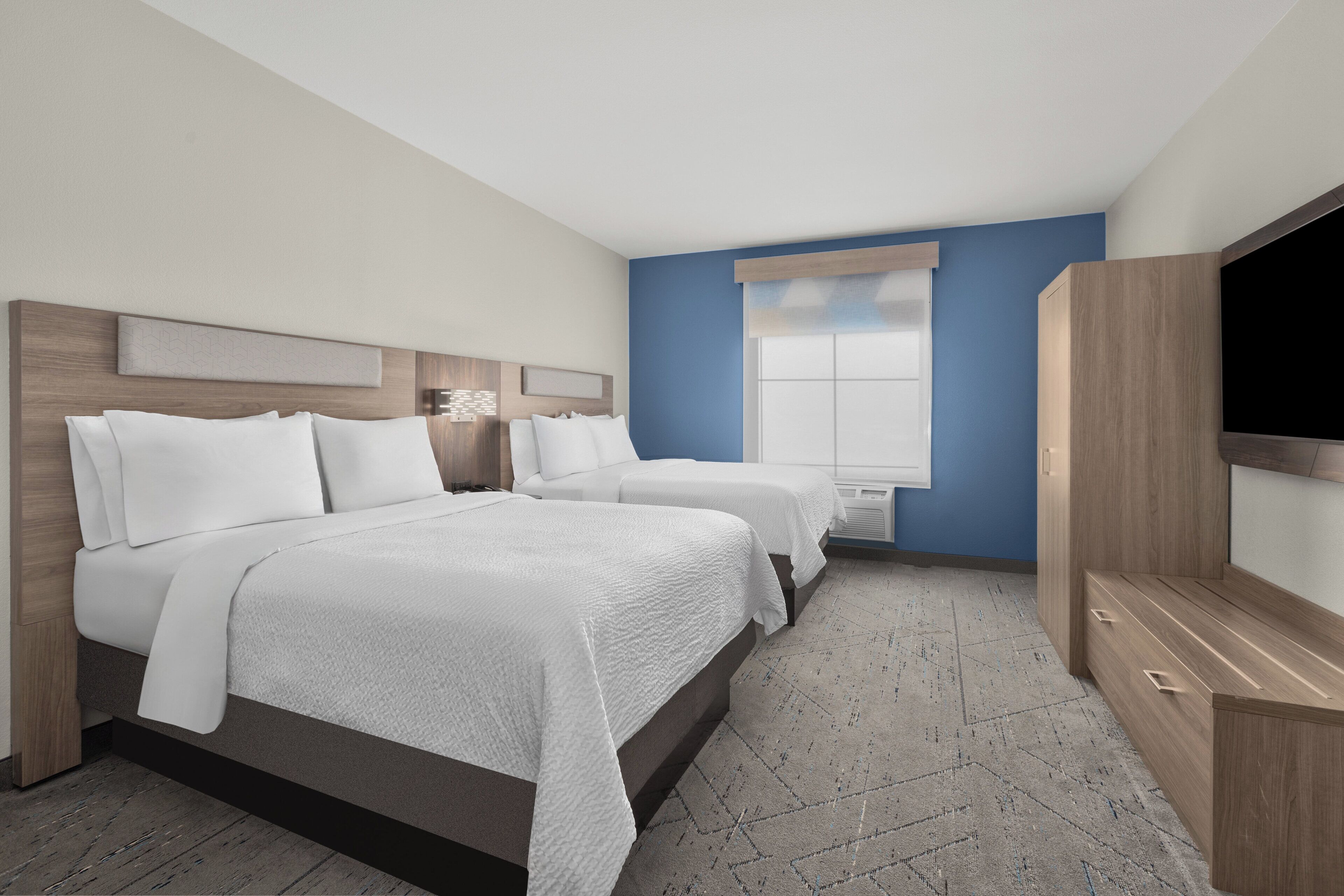 Ett hotellrum med två sängar, en TV och ett stort fönster.