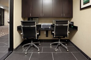 Sala de conferências com duas cadeiras de escritório pretas, um computador de mesa e uma impressora.