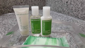 Una encimera de baño con una bandeja de plástico transparente que contiene tres productos de Bath & Body Works: loción corporal, champú y acondicionador.