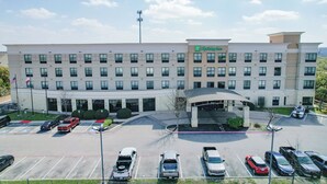 A multi-story hotel with a central entrance, parking lot, and American flag. - Holiday Inn San Antonio N - Stone Oak Area by IHG (San Antonio)