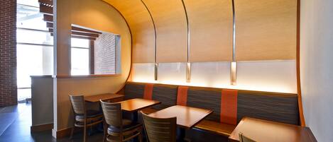 Un restaurante con asientos tipo cabina, mesas y sillas de madera.