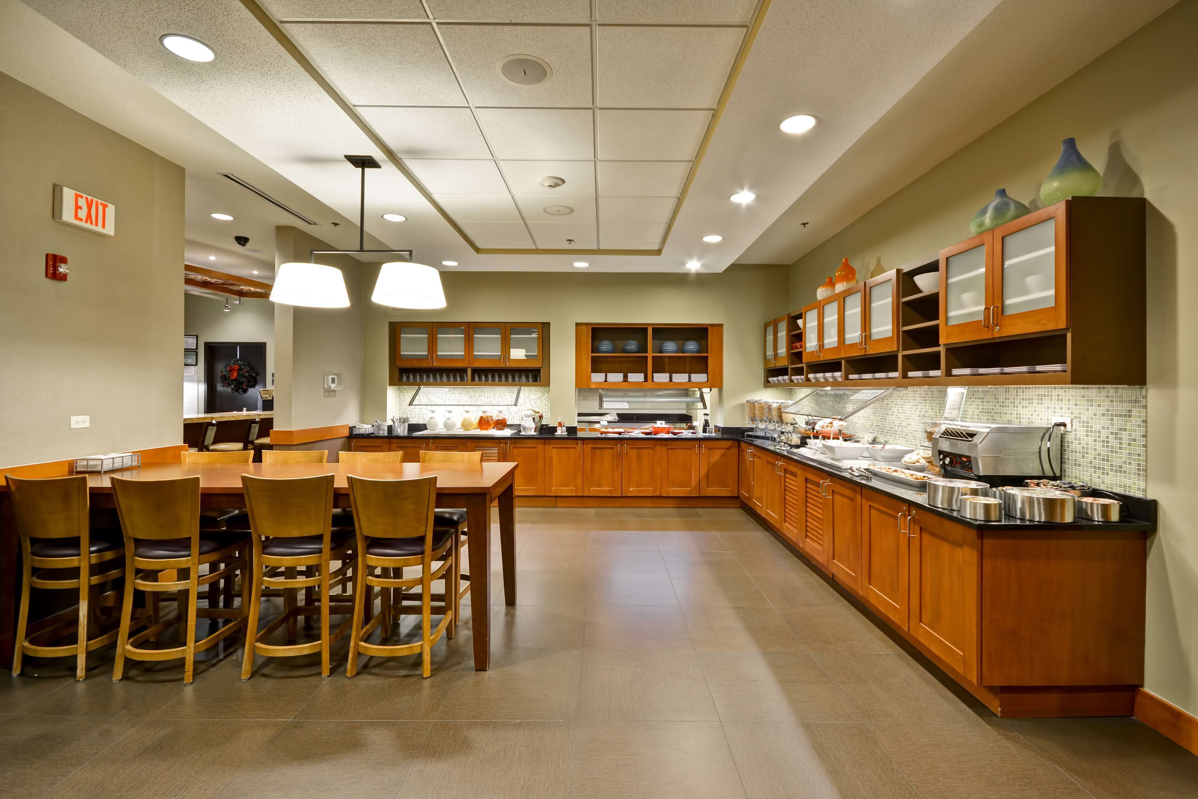 Una cocina amplia con armarios de madera, una isla central e iluminación colgante.