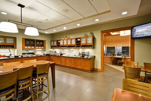 A modern kitchen with wooden cabinets, a central island, and a dining area with wooden tables and chairs.