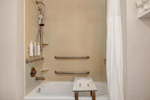 A bathroom with a bathtub, grab bars, a showerhead, and a towel rack.