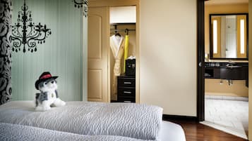 A hotel room with a bed, a wardrobe, a bathroom with a sink and mirror, and a small decorative item on the bed.